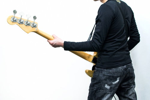 暗いステージでベースギターを構えるベーシストの後ろ姿