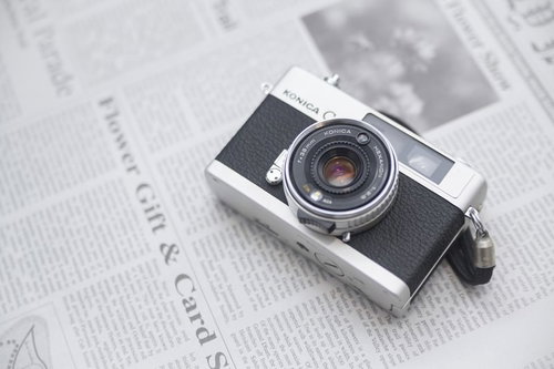 英文の新聞の上に置かれたレトロなフィルムカメラ