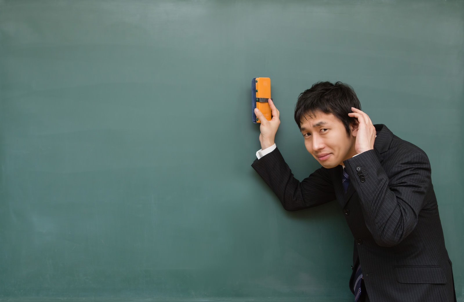 携帯電話を持って謝るスーツ姿の男性［モデル：大川竜弥］