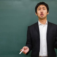 黒板の前で受験の重要性を真剣に語る塾講師の横姿の写真