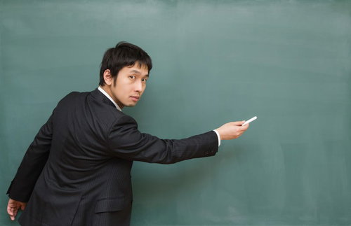 黒板の重要なポイントを指差して「ここ出ますよ！」と力説する先生