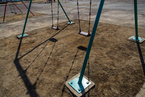 誰もいない昼下がりの公園のベンチとブランコの風景