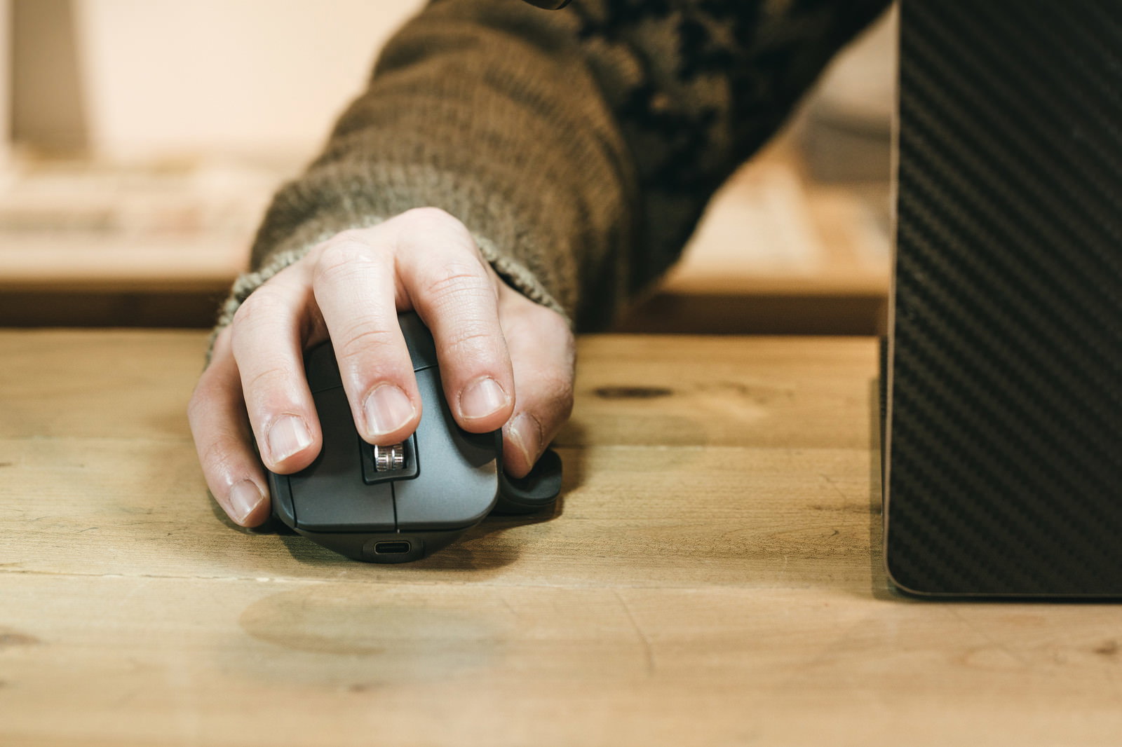 Right hand operating a mouse on a wooden desk