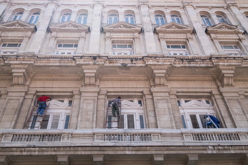 キューバのハバナで脚立を使って外壁を清掃するホテルの建物