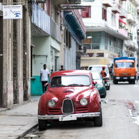 キューバの街角に路肩駐車している赤いSAABのクラシックカーの写真