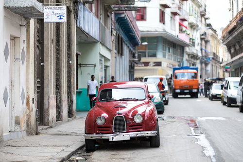 キューバの街角に路肩駐車している赤いSAABのクラシックカー