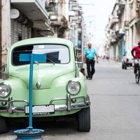 ハバナの街並みに停車する緑色のSAABクラシックカーの写真