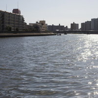 河川沿いの街並みと水面の風景、マンションと建物が立ち並ぶ都市景観の写真