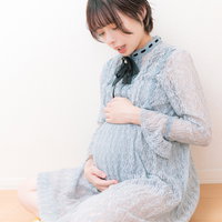 胎動を感じるお腹に手を当てた臨月の妊婦の写真