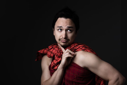 赤いチェック柄のマサイ族衣装を着て考え事をするドイツ人ハーフ男性