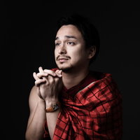 赤いチェック柄シャツで両手を合わせて祈りを捧げる男性の写真