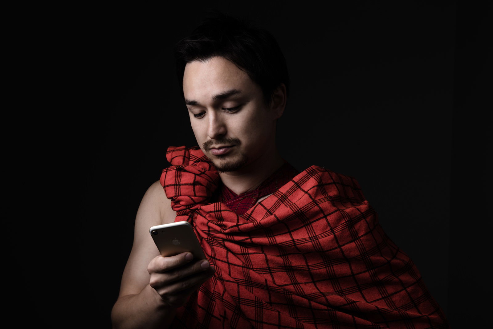 民族衣装でスマートフォンを操作する男性［モデル：Max_Ezaki］