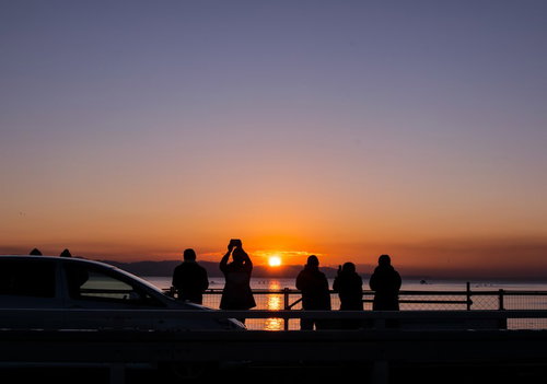 初日の出を撮影しようと集まる人々のシルエット