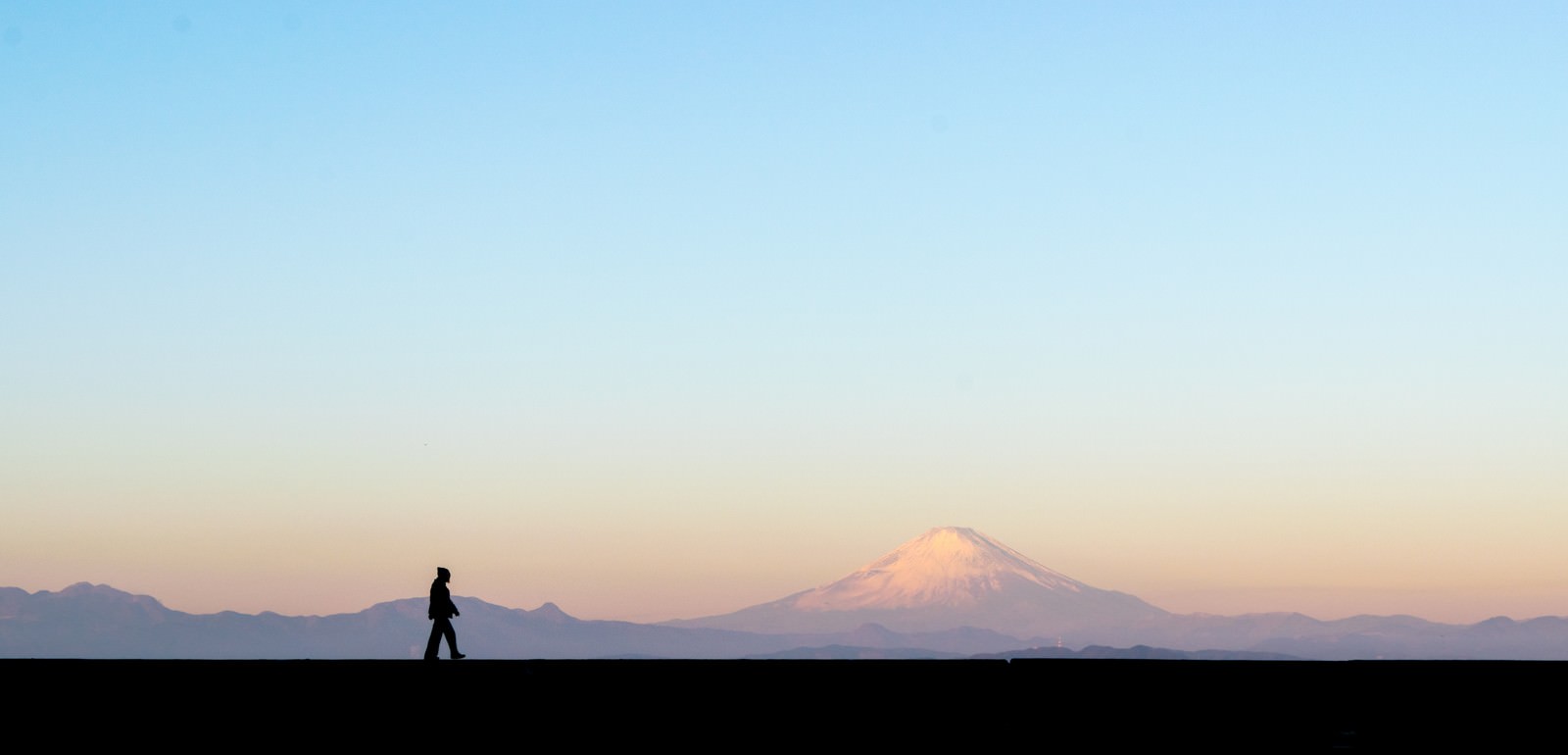 夕暮れの富士山を背景に散歩する男性のシルエット