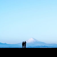 快晴の富士山を背景に寄り添うカップルのシルエットの写真
