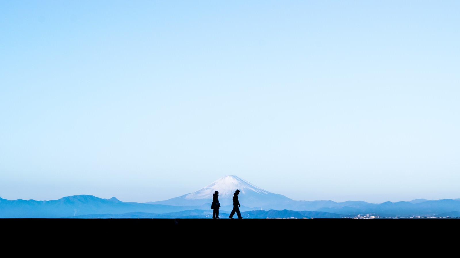 富士山を背景に青空の下を歩く恋人のシルエット