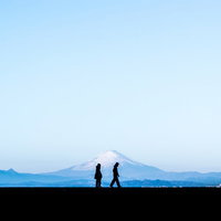 富士山を背景に見ながら散歩する恋人のシルエットの写真