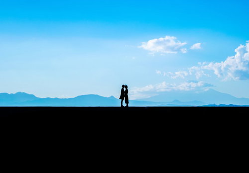 富士山を背景にした景色のいい堤防で顔を近づける恋人たち