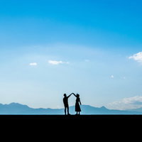 つないで手を離さないカップル（シルエット）の写真