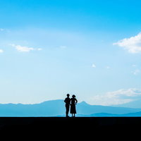 突然のプロポーズ、青空の下で手を繋ぐカップルのシルエットの写真
