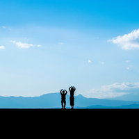 堤防の上でウッキーポーズをとる恋人たちのシルエットの写真