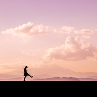 夕焼け空を背景に足を高く上げて散歩するシルエット女性の写真