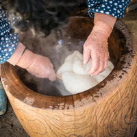 臼の中のつきたて餅をひっくり返すばっちゃんの手の写真