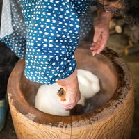 つきたての餅を臼の中で返すお婆さんの手元の写真