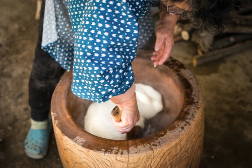 つきたての餅を臼の中で返すお婆さんの手元