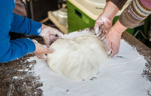 つきたての餅に餅とり粉（片栗粉）をつける手の動作