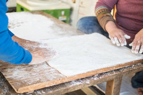 つきたての餅を木製の板の上で餅とり粉をまぶしながら伸ばす