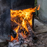 かまどに薪を入れて炎が燃え上がる様子の写真