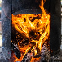 釜戸で薪を燃やす赤い炎が勢いよく燃え上がる様子の写真