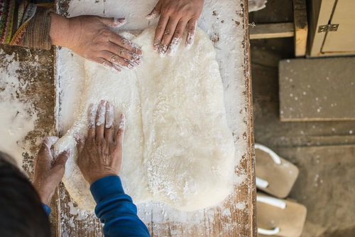つきたてのお餅を小判型に引き伸ばす作業風景