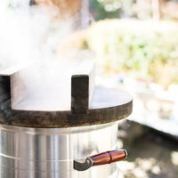 釜戸の鍋から立ち上る蒸気でもち米を蒸す様子の写真