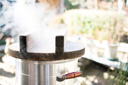 釜戸の鍋から立ち上る蒸気でもち米を蒸す様子