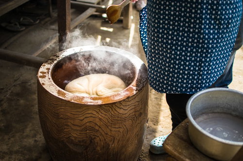 木臼でついたつきたての餅、湯気立ち上る伝統的な正月の餅つき