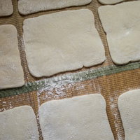 ござの上に並ぶ正方形に整えられた手作りの餅の写真