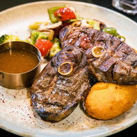 骨付きマトンステーキと焼き野菜の盛り付けプレートの写真