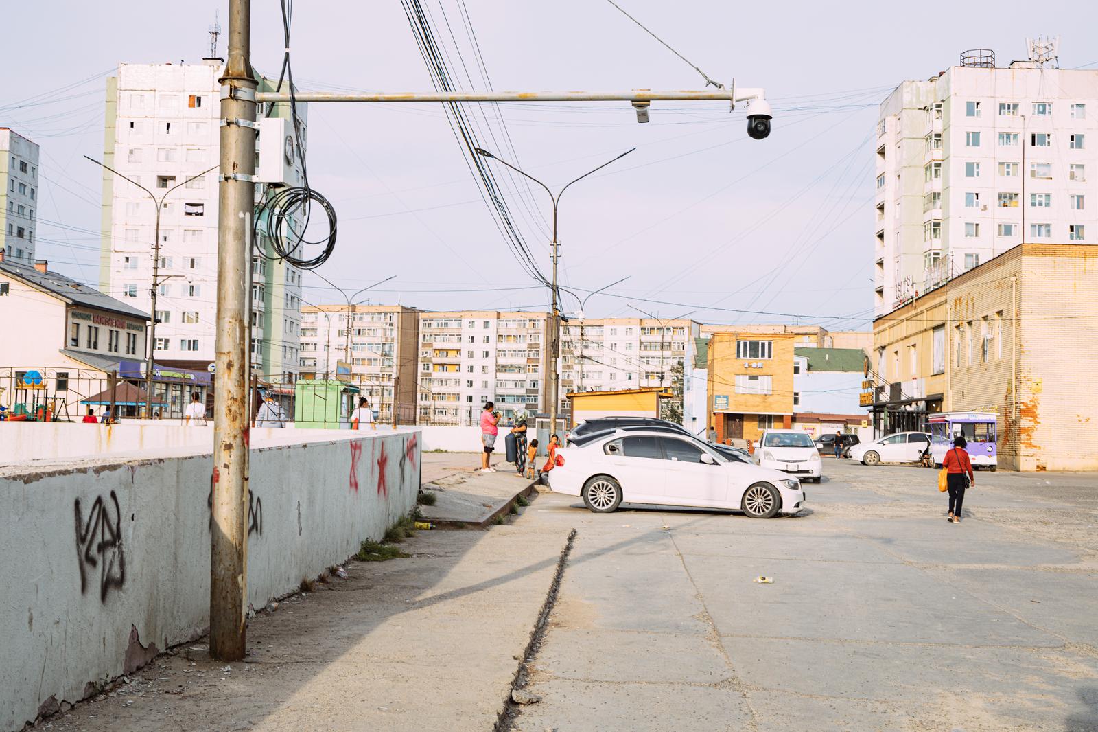 モンゴルの集合住宅と駐車場が並ぶ街角風景。複数の白い車が停まっている