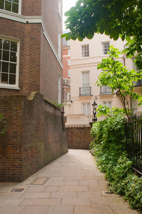 茶色いレンガ壁と鉄柵に挟まれた石畳の通路のウエストミンスター