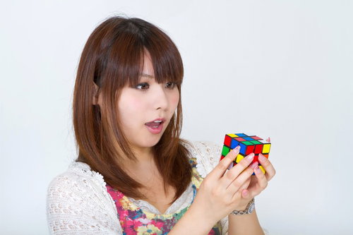 ルービックキューブを両手で持ち驚いた表情の女性