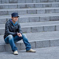 白い壁の前で階段に座り込んで俯く落ち込んだ男性の写真