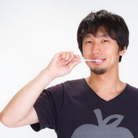 鏡の前で歯ブラシを持って笑顔でハミガキをする男性の写真