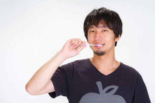 鏡の前で歯ブラシを持って笑顔でハミガキをする男性