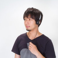 目を閉じてヘッドフォンで音楽を楽しむ男性の写真