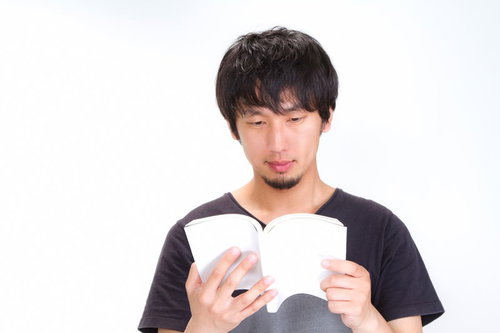 ソファーに座って開いた本を読む男性の横姿