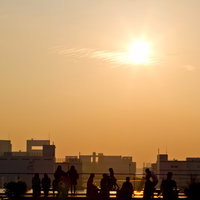 オレンジの夕焼け空を背景に歩く人々のシルエットの写真