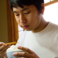 ご飯を頬張ってウマウマと食べる男性の食事風景の写真