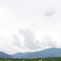 田んぼと山々が連なる曇り空の田園風景の写真